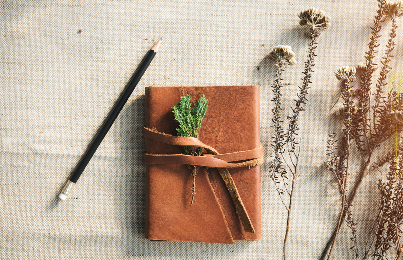 Leather personal journal with flowers on desk